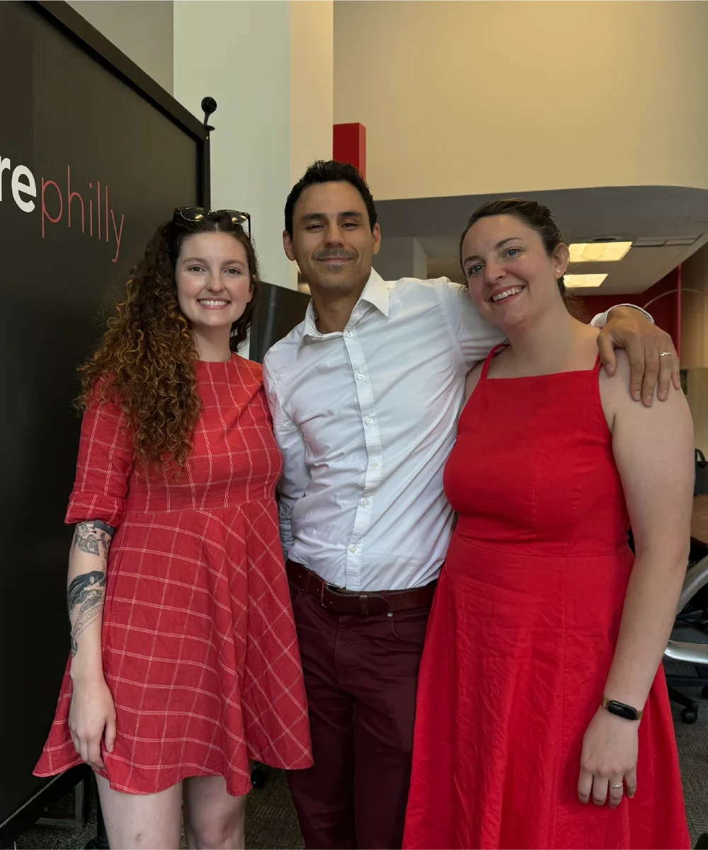 Happy couple celebrating their closing day with their realtor, all smiles and excitement. Both women are wearing red dresses, marking the special occasion