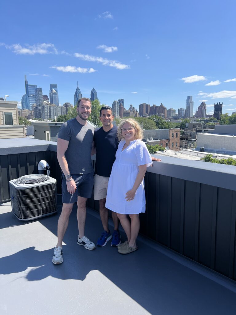 happy homebuyers posing on the roof of their new home with their real estate agent Teresa Boyer